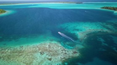 4K Hava Aracı, Bora Bora, Tahiti, Fransız Polinezyası 'ndaki turkuaz mavi gölde seyir halindeki bir tekne görüntüsü. Lüks, romantik tatil, balayı için egzotik bir yer..