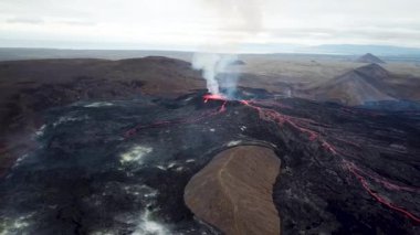 Geldingadalir, Reykjanes, İzlanda 'daki Fagradalsjall volkanik patlamasının 4K hava aracı görüntüleri. Sıcak Lav Nehri dumanla çevrili tepeden aşağı akıyor. İzlanda Volkanik Patlaması Grindavik