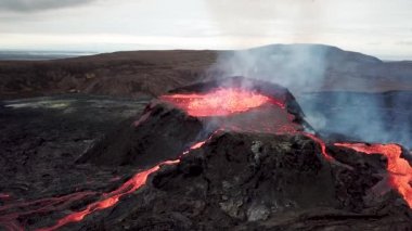 Geldingadalir, Reykjanes, İzlanda 'daki Fagradalsjall volkanik patlamasının 4K hava aracı görüntüleri. Sıcak Lav Nehri dumanla çevrili tepeden aşağı akıyor. İzlanda Volkanik Patlaması Grindavik