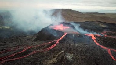 Geldingadalir, Reykjanes, İzlanda 'daki Fagradalsjall volkanik patlamasının 4K hava aracı görüntüleri. Sıcak Lav Nehri dumanla çevrili tepeden aşağı akıyor. İzlanda Volkanik Patlaması Grindavik