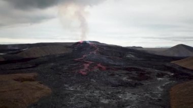 Geldingadalir, Reykjanes, İzlanda 'daki Fagradalsjall volkanik patlamasının 4K hava aracı görüntüleri. Sıcak Lav Nehri dumanla çevrili tepeden aşağı akıyor. İzlanda Volkanik Patlaması Grindavik