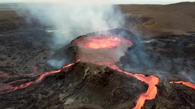 Geldingadalir, Reykjanes, İzlanda 'daki Fagradalsjall volkanik patlamasının 4K hava aracı görüntüleri. Sıcak Lav Nehri dumanla çevrili tepeden aşağı akıyor. İzlanda Volkanik Patlaması Grindavik