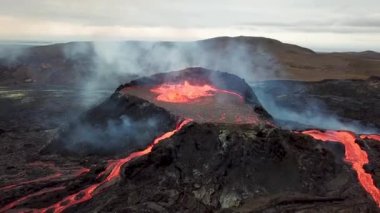 Geldingadalir, Reykjanes, İzlanda 'daki Fagradalsjall volkanik patlamasının 4K hava aracı görüntüleri. Sıcak Lav Nehri dumanla çevrili tepeden aşağı akıyor. İzlanda Volkanik Patlaması Grindavik