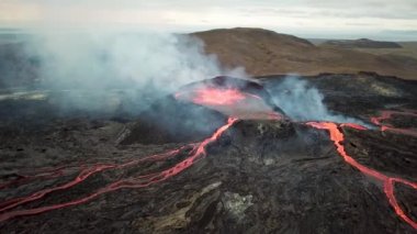 Geldingadalir, Reykjanes, İzlanda 'daki Fagradalsjall volkanik patlamasının 4K hava aracı görüntüleri. Sıcak Lav Nehri dumanla çevrili tepeden aşağı akıyor. İzlanda Volkanik Patlaması Grindavik