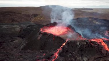 Geldingadalir, Reykjanes, İzlanda 'daki Fagradalsjall volkanik patlamasının 4K hava aracı görüntüleri. Sıcak Lav Nehri dumanla çevrili tepeden aşağı akıyor. İzlanda Volkanik Patlaması Grindavik