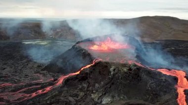 Geldingadalir, Reykjanes, İzlanda 'daki Fagradalsjall volkanik patlamasının 4K hava aracı görüntüleri. Sıcak Lav Nehri dumanla çevrili tepeden aşağı akıyor. İzlanda Volkanik Patlaması Grindavik