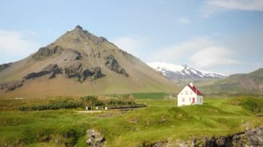 Arnarstapi village in Iceland. Small white church with huge moutains in the back. High quality 4k footage. Stapafell mountain and Snaefellsjokull glacier.