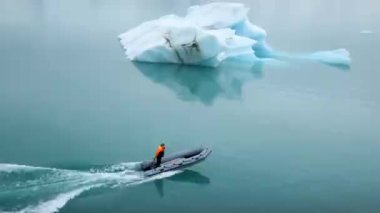 JOKULSARLON, ICELAND - January 23, 22: A man driving zodiac boat between icebergs in a melting glacier lagoon at Jokulsarlon, Iceland.