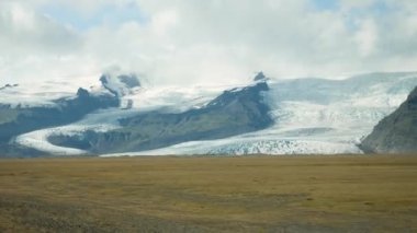 İzlanda 'da araba kullanmak. Arka planda çarpıcı bir buzulla İzlanda manzarası. İzlanda doğası. Yüksek kalite 4k görüntü