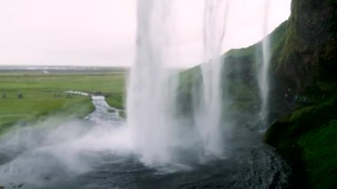 Standing behind Seljalandsfoss Waterfall in the South of Iceland. Seljalandsfoss, Icelands famous Ring Road waterfall. 