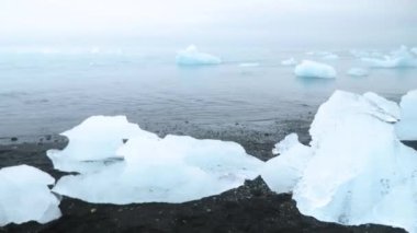 Diamond beach in Iceland. Icebergs on a black volcanic beach, Chunk of Ice on Diamond Beach. Global warming Concept. Dramatic weather. High quality 4k footage