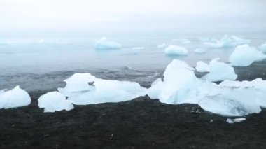 Diamond beach in Iceland. Icebergs on a black volcanic beach, Chunk of Ice on Diamond Beach. Global warming Concept. Dramatic weather. High quality 4k footage
