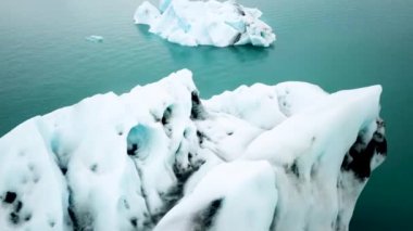 İzlanda 'daki Jokulsarlon buzul gölünde yüzen buzdağlarının insansız hava aracı görüntüleri. Buz dağlarının manzarası. Artistik buz tabakası. İzlanda 'da eriyen buzullar. Küresel ısınma, iklim değişikliği.
