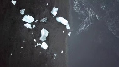 Aerial drone footage of Diamond beach, Iceland. Icebergs washed up on the black beach. Ice diamonds floating in diamond beach in Iceland. Scenic view of an Artic nature ice landscape. Climate change.