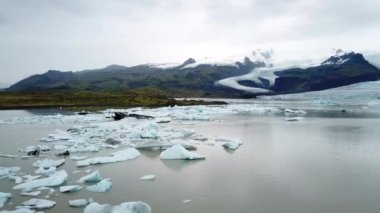 İzlanda 'da gölde yüzen bir sürü buzdağıyla Fjallsarlon buzul gölünün insansız hava aracı görüntüleri. Buz dağlarının manzarası. Artistik buz tabakası. İzlanda 'da eriyen buzullar. İklim değişikliği
