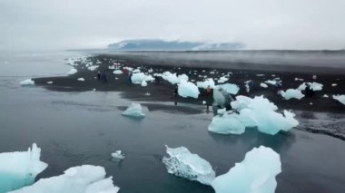Aerial drone footage of Diamond beach, Iceland. Icebergs washed up on the black beach. Ice diamonds floating in diamond beach in Iceland. Scenic view of an Artic nature ice landscape. Climate change.