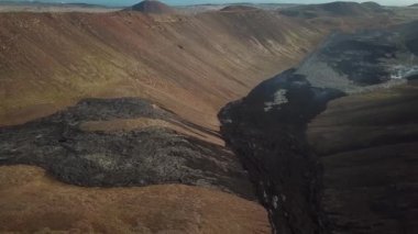 Fagradalsjall 'ın 4K hava aracı görüntüleri Geldingadalir, Reykjanes, İzlanda' da hafif aktif bir volkan patlaması. Duman ve dramatik gökyüzü ile çevrili soğuk lav. İzlanda Volkanik Patlaması Grindavik.