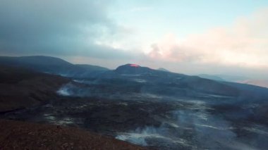 Geldingadalir, Reykjanes, İzlanda 'daki Fagradalsjall volkanik patlamasının 4K hava aracı görüntüleri. Sıcak Lav Nehri dumanla çevrili tepeden aşağı akıyor. İzlanda Volkanik Patlaması Grindavik