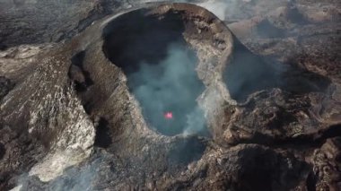 Fagradalsjall 'ın 4K hava aracı görüntüleri Geldingadalir, Reykjanes, İzlanda' da hafif aktif bir volkan patlaması. Duman ve dramatik gökyüzü ile çevrili soğuk lav. İzlanda Volkanik Patlaması Grindavik.