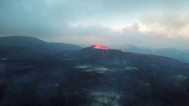 Geldingadalir, Reykjanes, İzlanda 'daki Fagradalsjall volkanik patlamasının 4K hava aracı görüntüleri. Sıcak Lav Nehri dumanla çevrili tepeden aşağı akıyor. İzlanda Volkanik Patlaması Grindavik