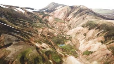 Landmannalaugar 'ın etrafındaki muhteşem dağların olduğu bir İzlanda manzarasının 4K sinematik hava aracı görüntüleri. İzlanda 'da gökkuşağı dağları. Blahnjukur ve Laugahraun. Yosun kaplı lav alanları, İzlanda