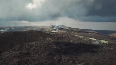 Fagradalsjall 'ın 4K hava aracı görüntüleri Geldingadalir, Reykjanes, İzlanda' da hafif aktif bir volkan patlaması. Duman ve dramatik gökyüzü ile çevrili soğuk lav. İzlanda Volkanik Patlaması Grindavik.