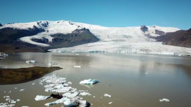 İzlanda 'da gölde yüzen bir sürü buzdağıyla Fjallsarlon buzul gölünün insansız hava aracı görüntüleri. Buz dağlarının manzarası. Artistik buz tabakası. İzlanda 'da eriyen buzullar. İklim değişikliği