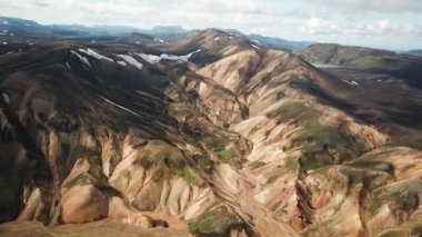 Landmannalaugar 'ın etrafındaki muhteşem dağların olduğu bir İzlanda manzarasının 4K sinematik hava aracı görüntüleri. İzlanda 'da gökkuşağı dağları. Blahnjukur ve Laugahraun. Yosun kaplı lav alanları, İzlanda