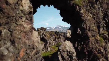 Kayanın camından uçarak. Arkadaki Snaefellsjokull buzulu kayadaki bir delikten görülebiliyor. Yüksek kalite 4K görüntü. İzlanda 'da dağlar ve buzullar. 
