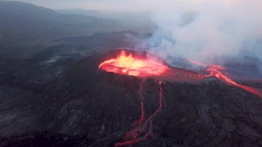Geldingadalir, Reykjanes, İzlanda 'daki Fagradalsjall volkanik patlamasının 4K hava aracı görüntüleri. Sıcak Lav Nehri dumanla çevrili tepeden aşağı akıyor. İzlanda Volkanik Patlaması Grindavik