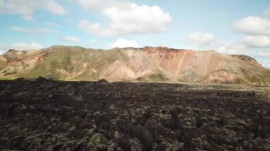 Landmannalaugar 'ın etrafındaki muhteşem dağların olduğu İzlanda hava aracı görüntüleri. İzlanda 'da gökkuşağı dağları. Yosun İzlanda 'daki lav tarlalarını kapladı. Yüksek kalite 4k görüntü