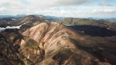 Landmannalaugar 'ın etrafındaki muhteşem dağların olduğu bir İzlanda manzarasının 4K sinematik hava aracı görüntüleri. İzlanda 'da gökkuşağı dağları. Blahnjukur ve Laugahraun. Yosun kaplı lav alanları, İzlanda