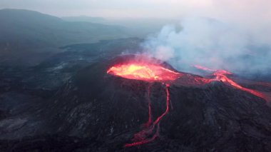 Geldingadalir, Reykjanes, İzlanda 'daki Fagradalsjall volkanik patlamasının 4K hava aracı görüntüleri. Sıcak Lav Nehri dumanla çevrili tepeden aşağı akıyor. İzlanda Volkanik Patlaması Grindavik