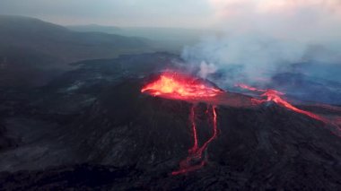 Geldingadalir, Reykjanes, İzlanda 'daki Fagradalsjall volkanik patlamasının 4K hava aracı görüntüleri. Sıcak Lav Nehri dumanla çevrili tepeden aşağı akıyor. İzlanda Volkanik Patlaması Grindavik