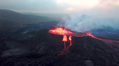 Geldingadalir, Reykjanes, İzlanda 'daki Fagradalsjall volkanik patlamasının 4K hava aracı görüntüleri. Sıcak Lav Nehri dumanla çevrili tepeden aşağı akıyor. İzlanda Volkanik Patlaması Grindavik