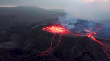 Geldingadalir, Reykjanes, İzlanda 'daki Fagradalsjall volkanik patlamasının 4K hava aracı görüntüleri. Sıcak Lav Nehri dumanla çevrili tepeden aşağı akıyor. İzlanda Volkanik Patlaması Grindavik