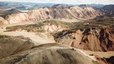 Landmannalaugar 'ın etrafındaki muhteşem dağların olduğu bir İzlanda manzarasının 4K sinematik hava aracı görüntüleri. İzlanda 'da gökkuşağı dağları. Blahnjukur ve Laugahraun. Yosun kaplı lav alanları, İzlanda