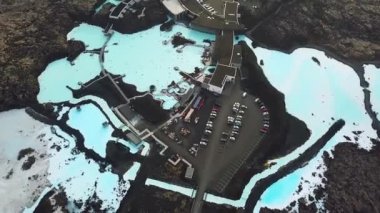 İzlanda 'daki Blue Lagoon Spa' nın 4K hava aracı görüntüleri. Jeotermal kaplıca. Mavi sular siyah toprakla çelişiyor. Açık doğal havuz üzerinde uçmak. Yüksek kalite 4k görüntü