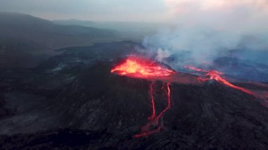 Geldingadalir, Reykjanes, İzlanda 'daki Fagradalsjall volkanik patlamasının 4K hava aracı görüntüleri. Sıcak Lav Nehri dumanla çevrili tepeden aşağı akıyor. İzlanda Volkanik Patlaması Grindavik