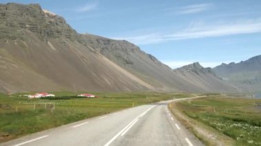 İzlanda 'da araba kullanmak. Etrafı çarpıcı dağlarla çevrili İzlanda yolu manzarası. Arka planda Stokksnes 'deki Vestrahorn. İzlanda doğası. Yüksek kalite 4k görüntü