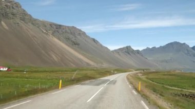 İzlanda 'da araba kullanmak. Etrafı çarpıcı dağlarla çevrili İzlanda yolu manzarası. Arka planda Stokksnes 'deki Vestrahorn. İzlanda doğası. Yüksek kalite 4k görüntü
