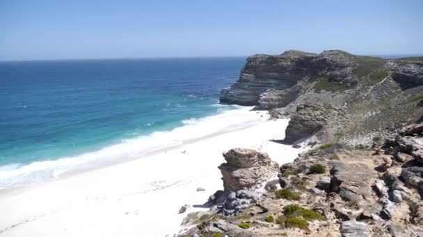 南アフリカ共和国ケープタウンのディアス ビーチの4K映像 ケープ半島の白い砂浜がある岩の崖とターコイズブルーのきれいな水 特定の動物や植物と岬ポイント自然保護区 — ストック動画