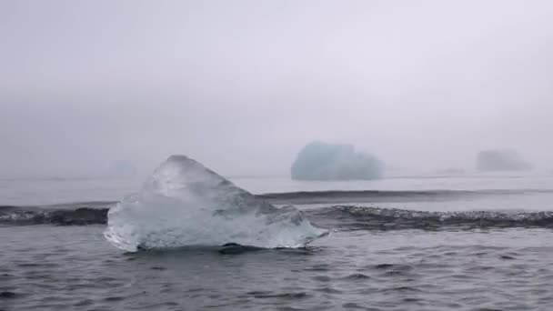 冰岛的钻石海滩在一个黑色的火山海滩上的一个巨大融化的冰山的特写 钻石海滩上的冰块块 全球变暖概念 多雾的阳光天气 高质量的4K镜头 — 图库视频影像