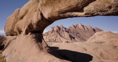 Afrika, Namibya 'daki Spitzkoppe dağındaki bir kaya camından uçan 4K hava aracı görüntüsü. Afrika 'nın antik kaya oluşumları, kırmızı kaya manzarası. Yürüyüş. Sinematik Yüksek Kaliteli Görüntüler.