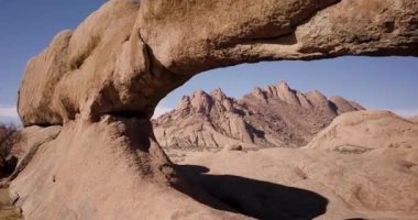 Afrika, Namibya 'daki Spitzkoppe dağındaki bir kaya camından uçan 4K hava aracı görüntüsü. Afrika 'nın antik kaya oluşumları, kırmızı kaya manzarası. Yürüyüş. Sinematik Yüksek Kaliteli Görüntüler.