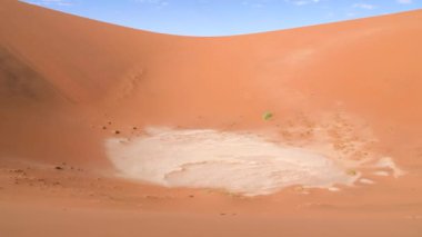 Sossusvlei 'de kırmızı çöl kum tepecikli kuru kil tavası ya da Namibya' da Susriem. Namib Çölü ve Deadvlei 'deki Büyük Baba kumulları. Mavi gökyüzü ve küçük bulutlu turuncu çöl. 4K Sinematik Görüntüler.