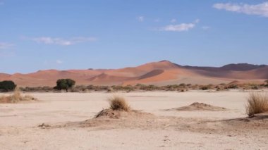 Sossusvlei 'de kırmızı çöl kum tepecikli kuru kil tavası ya da Namibya' da Susriem. Namib Çölü ve Deadvlei 'deki Büyük Baba kumulları. Mavi gökyüzü ve küçük bulutlu turuncu çöl. 4K Sinematik Görüntüler.