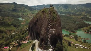Kolombiya, Medellin yakınlarındaki El Penon de Guatape 'in insansız hava aracı görüntüleri. Büyük ve benzersiz bir kaya. Tepeye çıkan merdivenleri var. Turistik bir yer. Kolombiya 'da büyük bir taş. Yüksek kalite 4k görüntü.