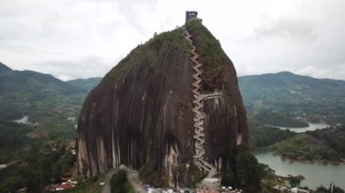 Kolombiya, Medellin yakınlarındaki El Penon de Guatape 'in insansız hava aracı görüntüleri. Büyük ve benzersiz bir kaya. Tepeye çıkan merdivenleri var. Turistik bir yer. Kolombiya 'da büyük bir taş. Yüksek kalite 4k görüntü.