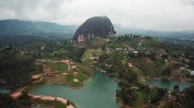 Kolombiya, Medellin yakınlarındaki El Penon de Guatape 'in insansız hava aracı görüntüleri. Büyük ve benzersiz bir kaya. Tepeye çıkan merdivenleri var. Turistik bir yer. Kolombiya 'da büyük bir taş. Yüksek kalite 4k görüntü.